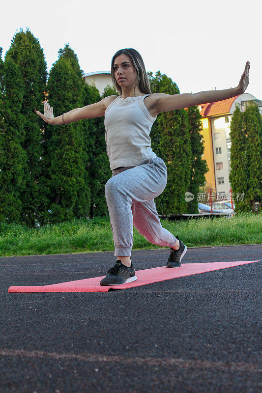Caucasian woman meditating and doing yoga on a mat in a public park